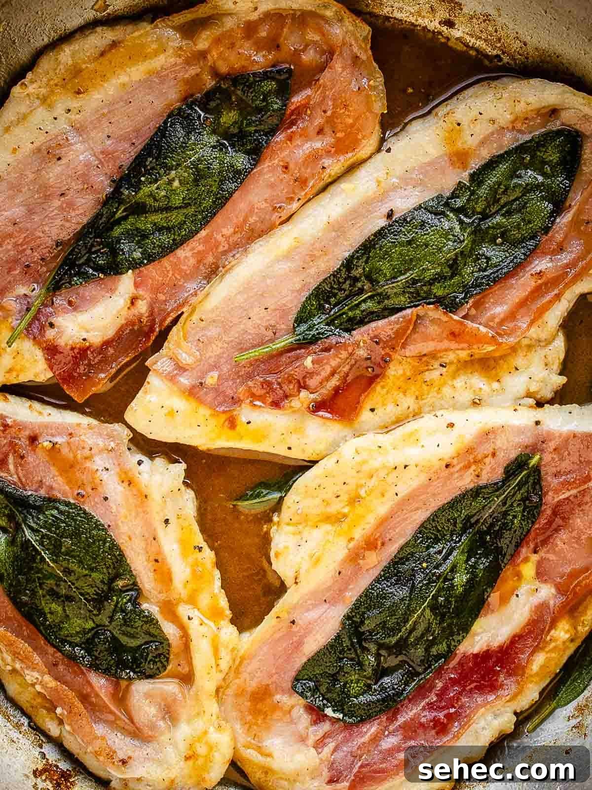 Chicken Saltimbocca with Prosciutto and Sage 12 Four chicken cutlets with prosciutto and a sage leaf on each in a pan viewed from above.