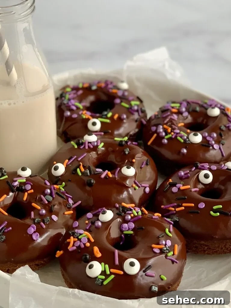 Double Chocolate Donuts with Rich Chocolate Glaze 5 A serving plate filled with 6 double chocolate donuts topped with chocolate ganache and Halloween themed sprinkles.