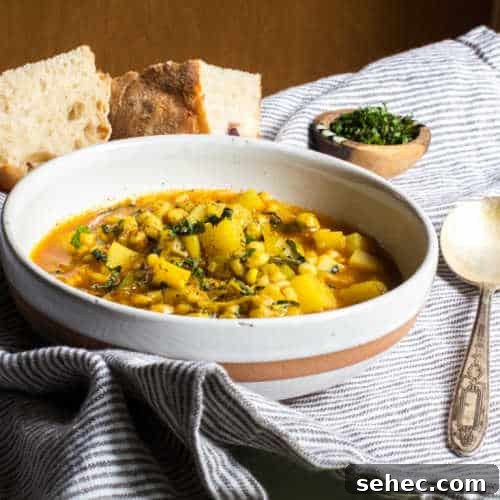 January Vegetarian Meal Plan Week 4 4 A bowl of vegetarian barley soup heaped with potatoes and mint, with some bread and extra mint in a small bowl.