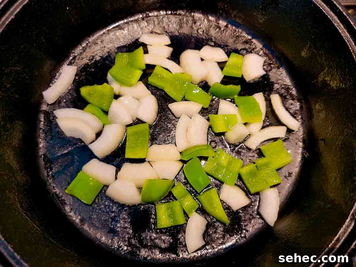 Creamy Shrimp and Rice Skillet 3 green pepper and onion frying in a skillet.