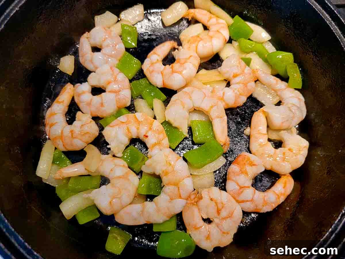 Creamy Shrimp and Rice Skillet 4 shrimp, green pepper and onion frying in a skillet.