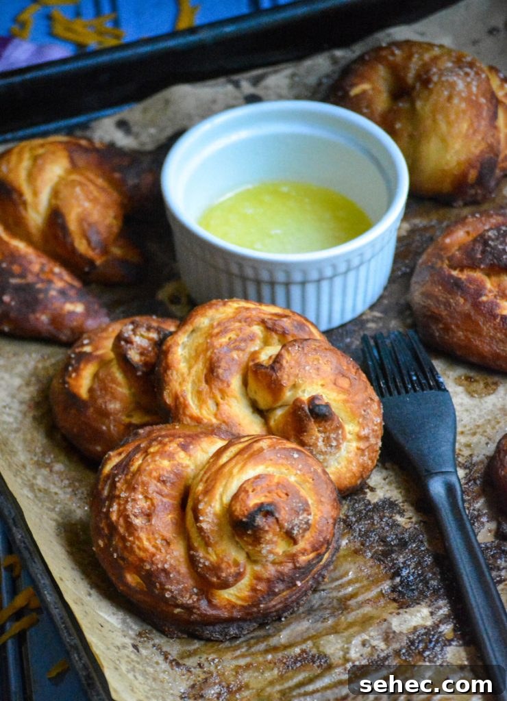 Soft Pretzels Made with Canned Biscuits 2 canned biscuit pretzels shown on brown parchment paper with a dish of melted butter