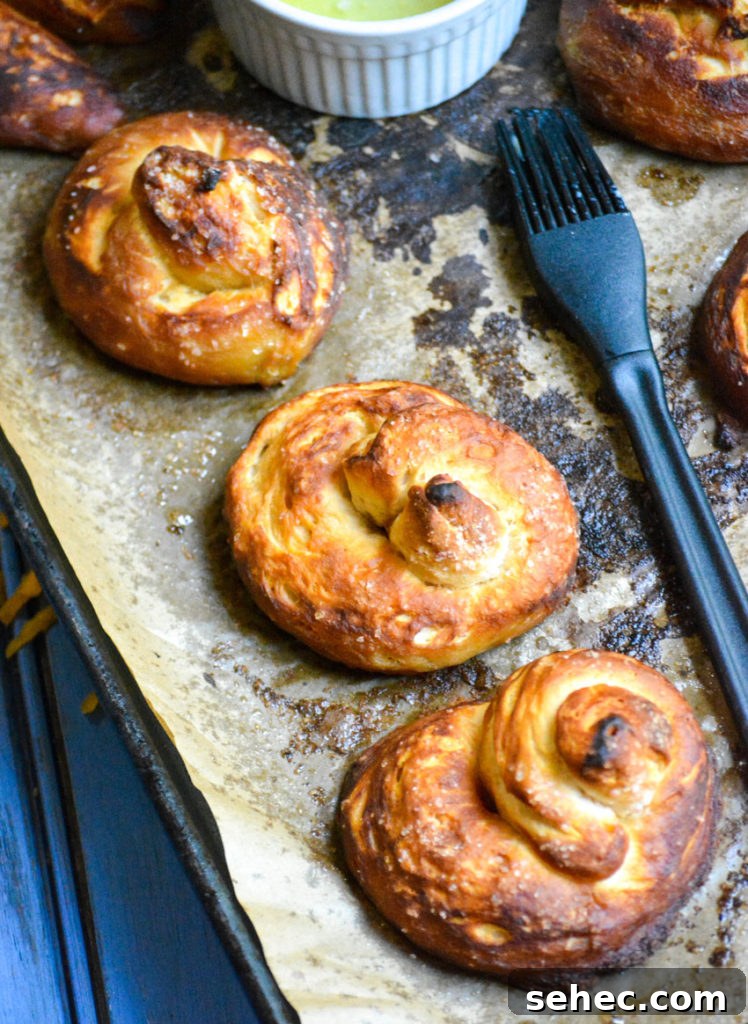 Soft Pretzels Made with Canned Biscuits 3 baked buttered canned biscuit pretzels shown on a sheet of brown parchment paper