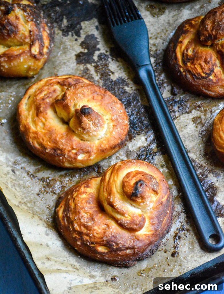 Soft Pretzels Made with Canned Biscuits 5 baked buttered canned biscuit pretzels shown on a sheet of brown parchment paper
