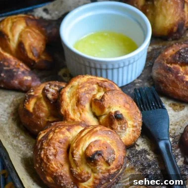 Soft Pretzels Made with Canned Biscuits 8 canned biscuit pretzels shown on brown parchment paper with a dish of melted butter