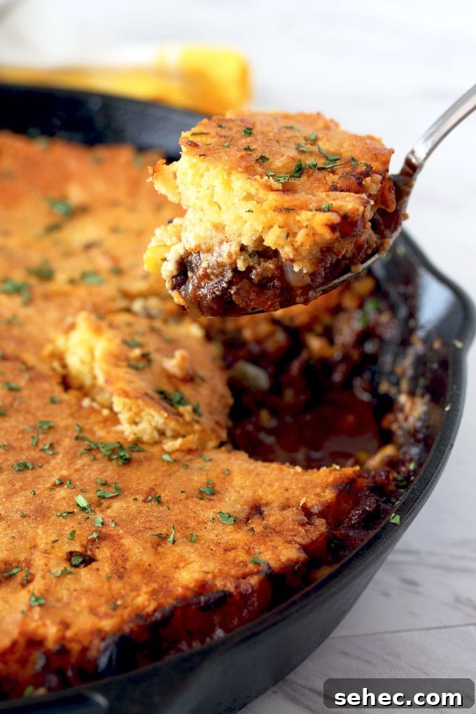 Brown Butter Cornbread Tamale Pie 3 View of a serving spoon scooping a portion of tamale pie off a cast iron skillet