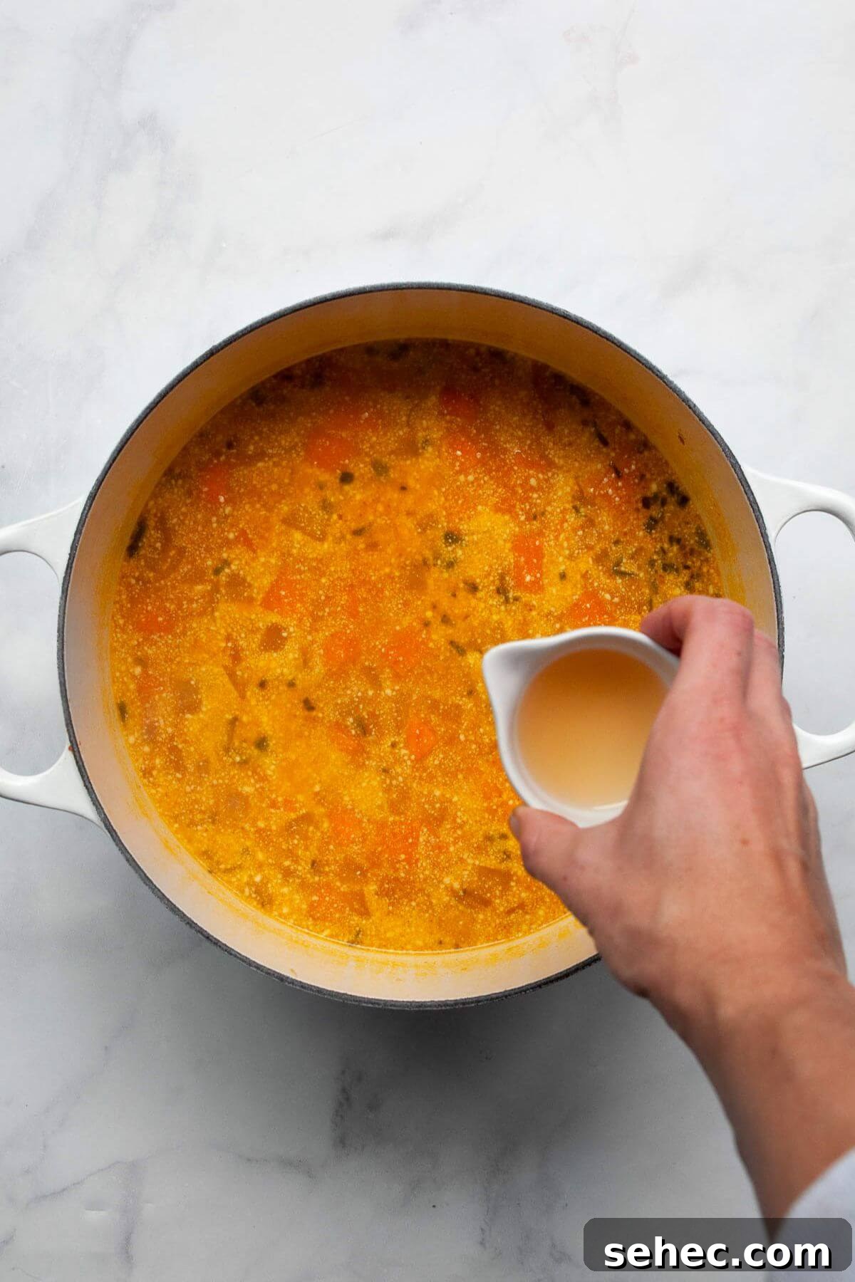 Creamy Pumpkin Sweet Potato Soup Recipe 6 Pouring apple cider vinegar into simmering sweet potato and pumpkin soup.
