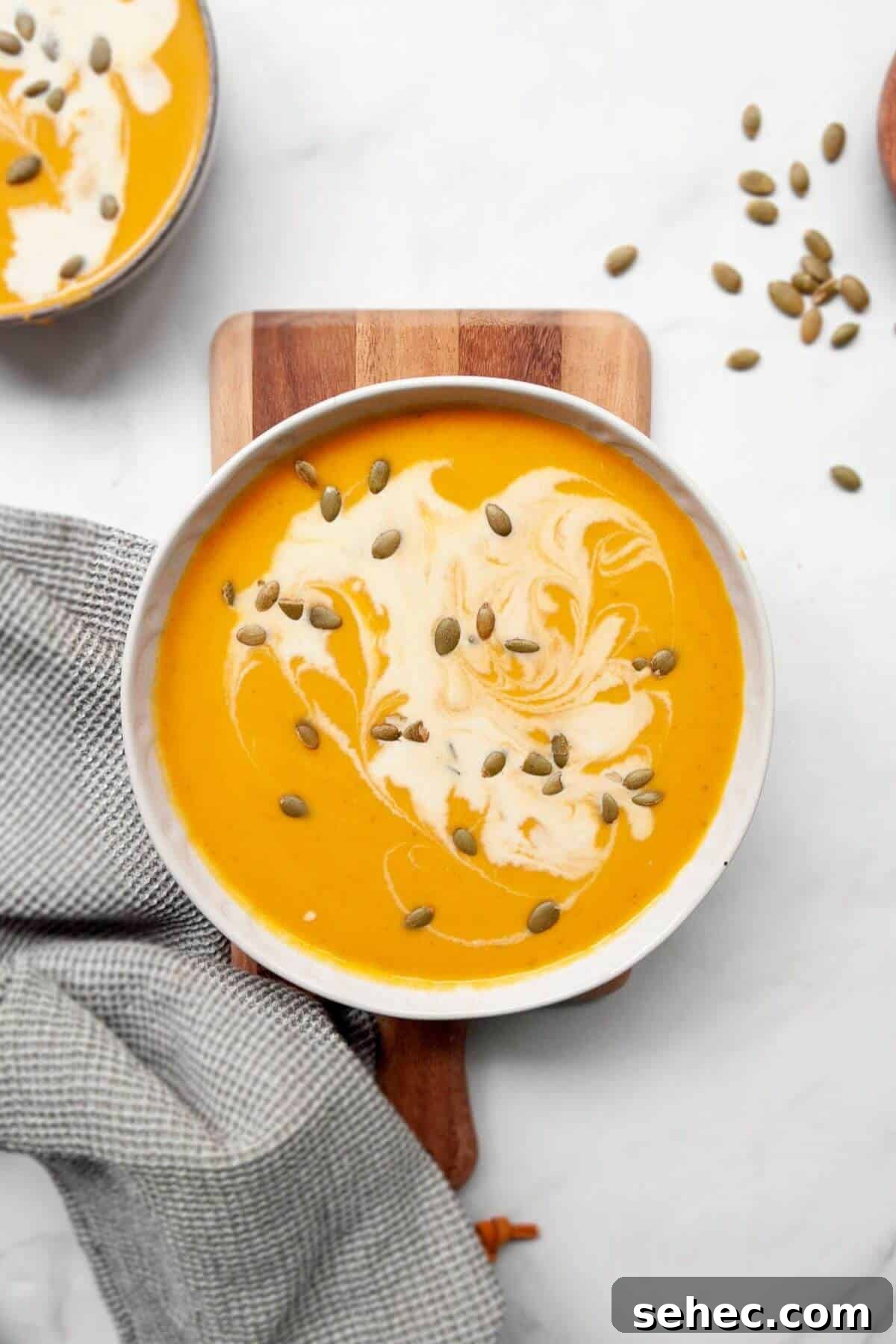 Creamy Pumpkin Sweet Potato Soup Recipe 8 Silky smooth pumpkin and sweet potato soup in a bowl with pumpkin seeds and coconut milk on top.