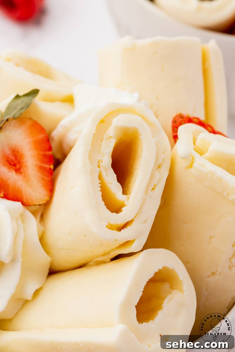 Closeup view of homemade rolled ice cream. It's vanilla flavored, and garnished with fresh strawberries.