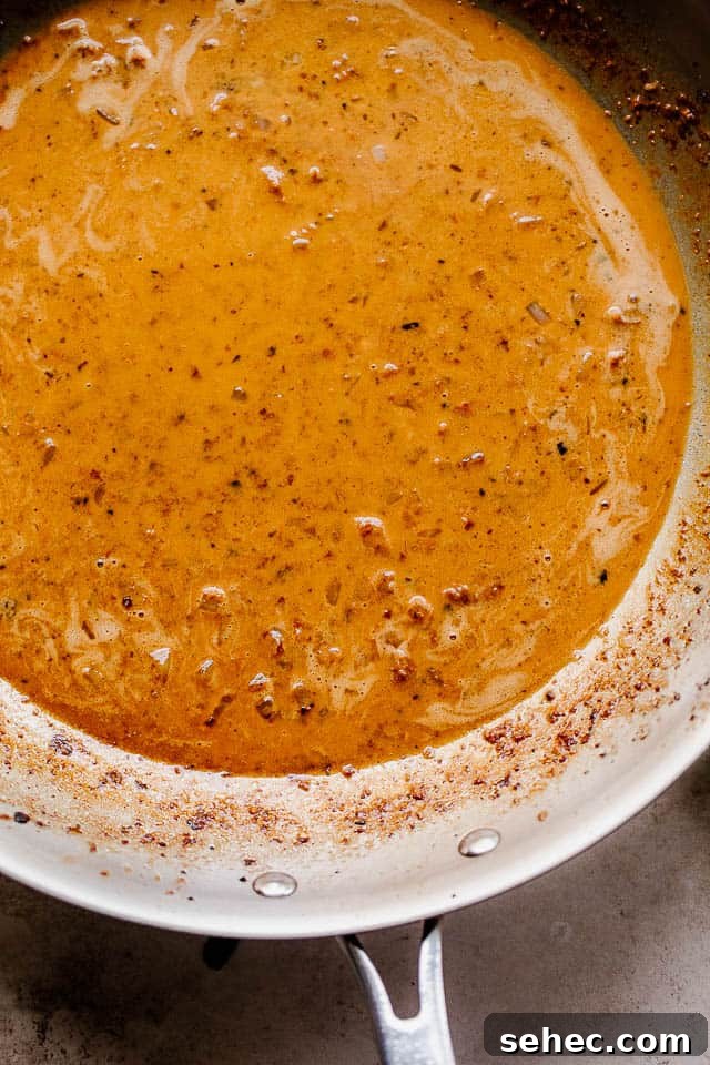 One Pot Creamed Spinach Chicken features tender, juicy chicken thighs smothered in a creamy sauce made with spinach, shallots, wine, and cream. overhead shot of heavy cream sauce in a skillet