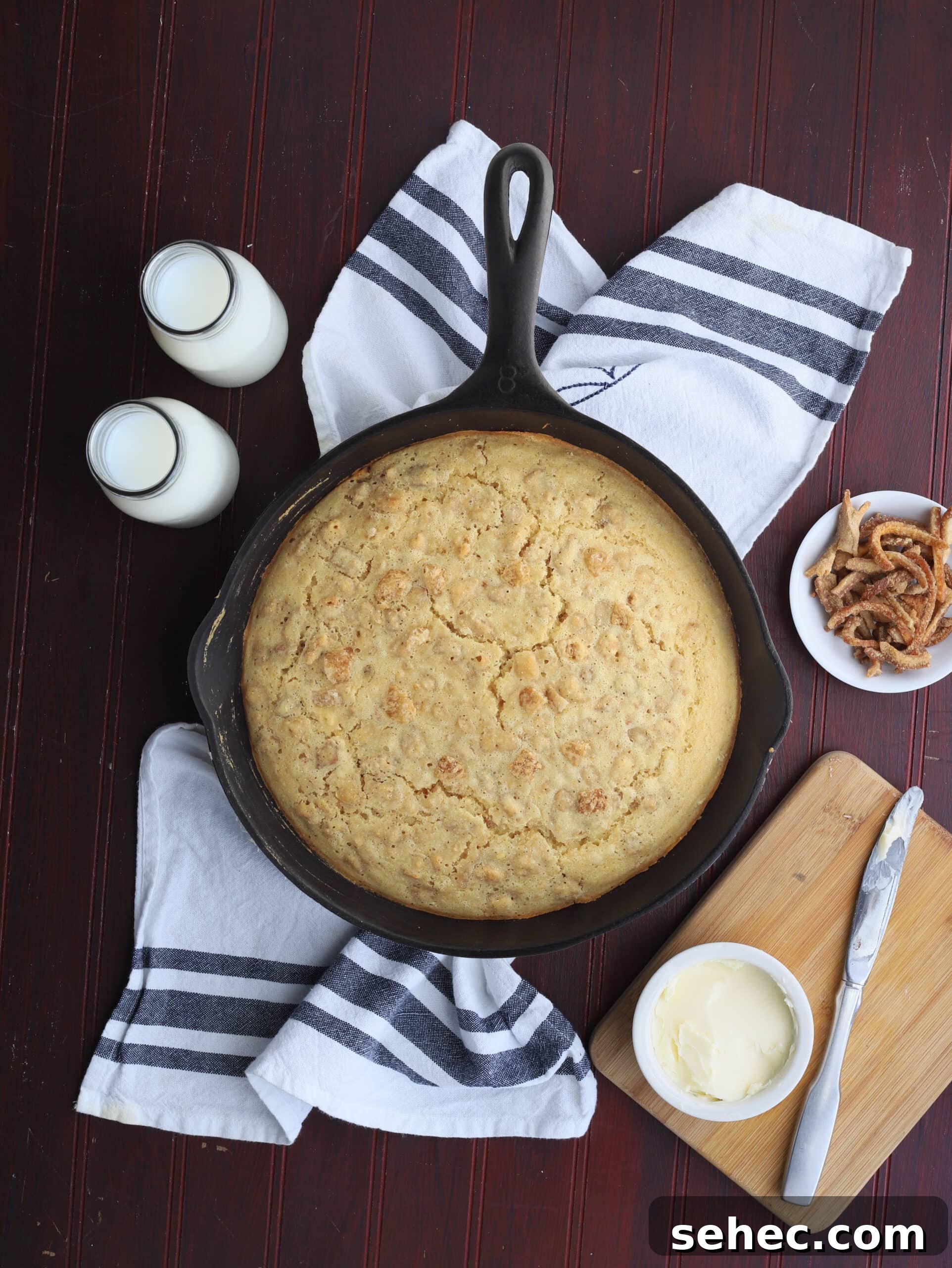 Southern Cracklin Cornbread Recipe 17 overhead shot of cracklin' corn bread in a cast iron skillet with butter, milk and a dish or cracklings to the side