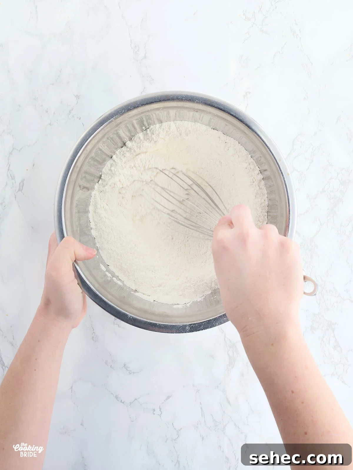 Southern Cracklin Cornbread Recipe 7 hand whisking dry corn bread ingredients together in a stainless steel mixing bowl