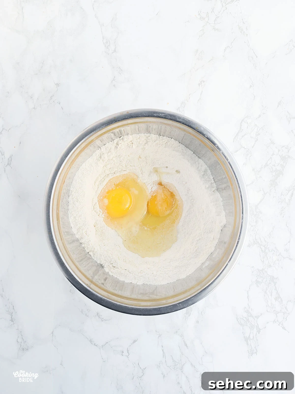 Southern Cracklin Cornbread Recipe 8 stainless steel bowl with dry corn bread ingredients and two eggs