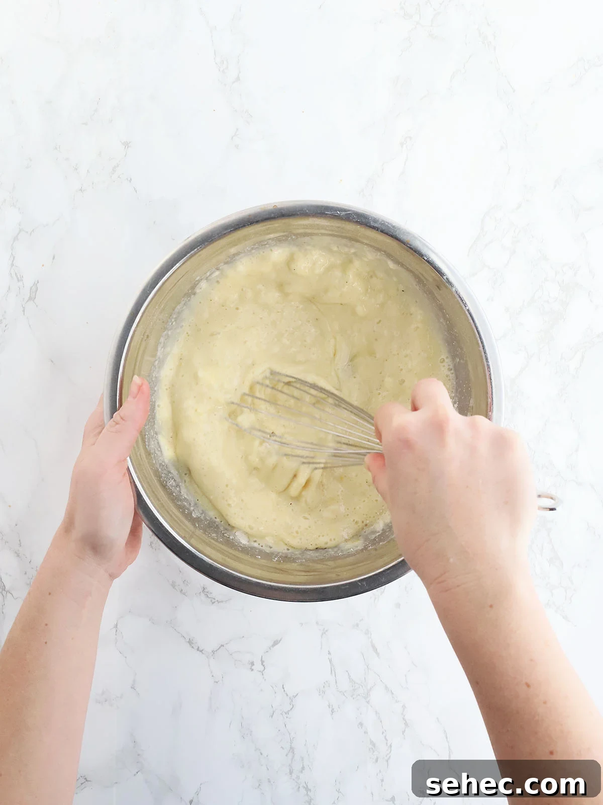 Southern Cracklin Cornbread Recipe 10 hands whisking corn bread batter in a stainless steel mixing bowl