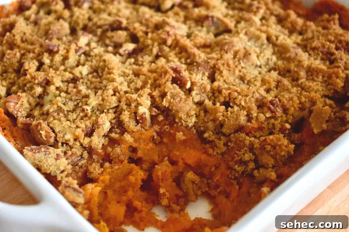 Eggless Sweet Potato Casserole with Pecan Streusel 6 Sweet Potato Casserole with pecan streusel topping in a white dish with a scoop removed.