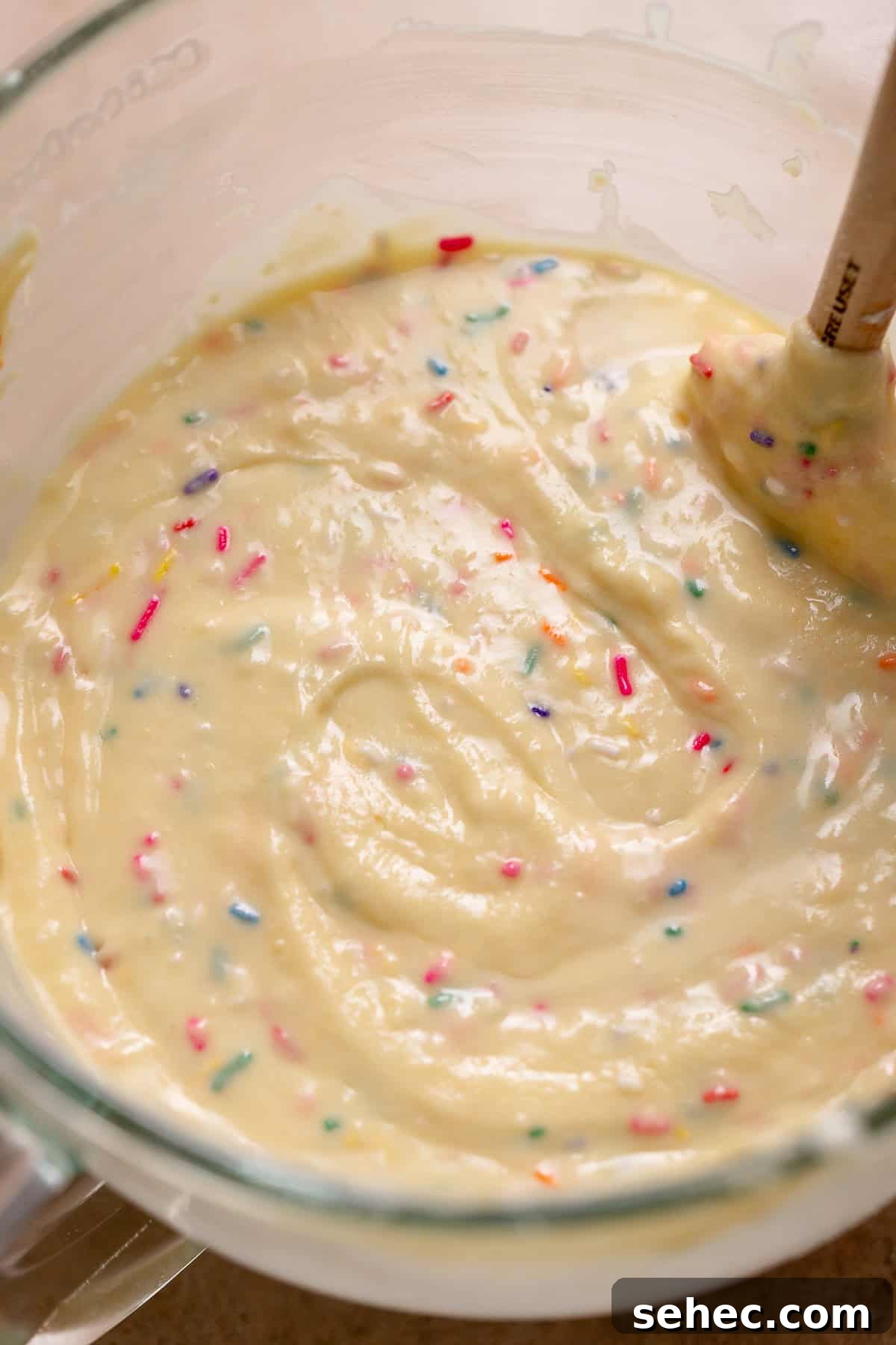 Birthday Cupcakes Recipe I Make Every Year 4 Smooth vanilla cupcake batter folded with rainbow sprinkles in a glass bowl, showing a thick, glossy texture before baking.