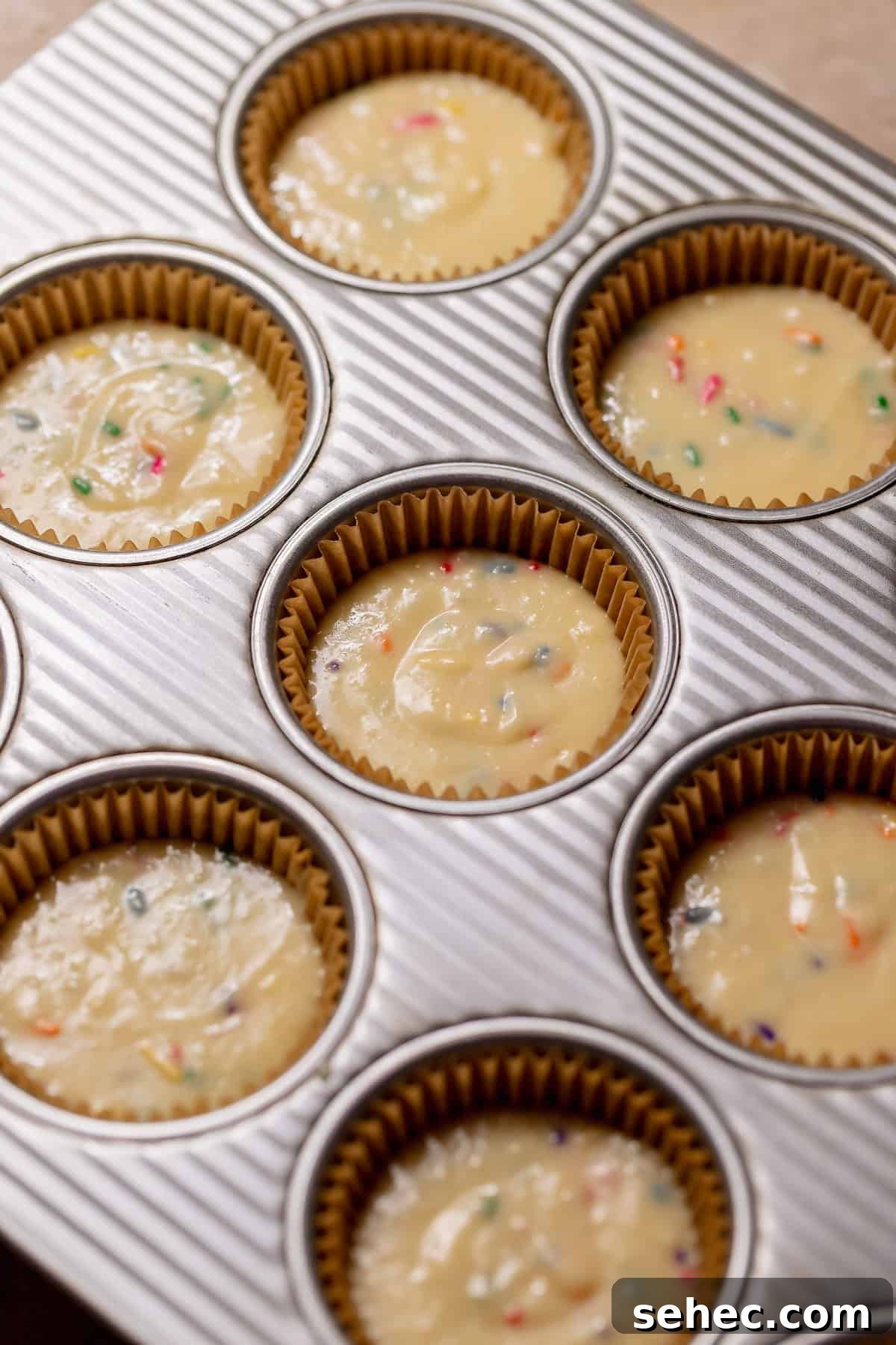 Birthday Cupcakes Recipe I Make Every Year 5 Funfetti cupcake batter spooned into lined muffin tins, speckled with rainbow sprinkles and ready to bake.