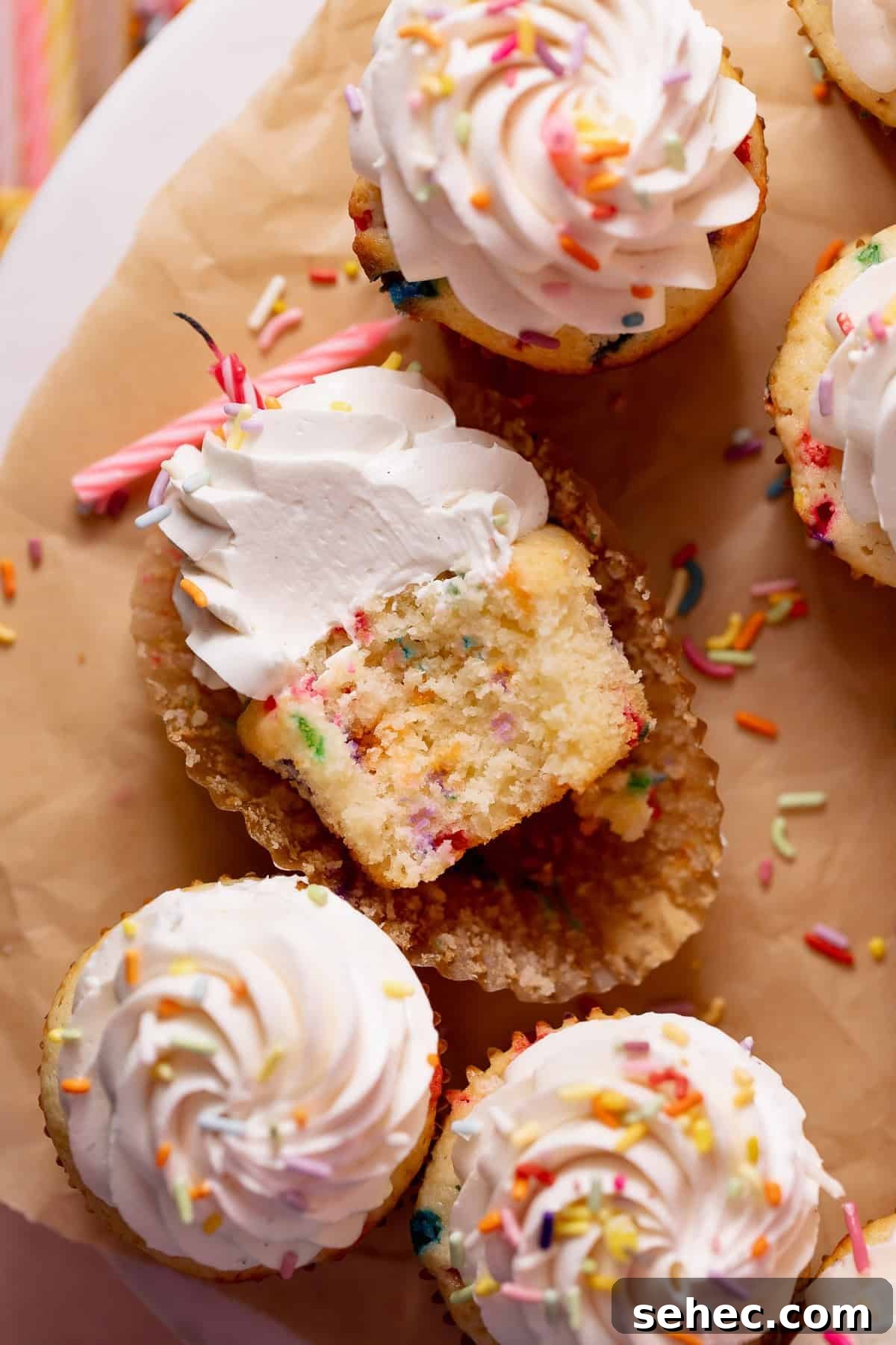 Birthday Cupcakes Recipe I Make Every Year 9 Close-up of a frosted birthday cupcake with a bite taken out, revealing a moist vanilla sprinkle cake crumb and creamy vanilla buttercream.