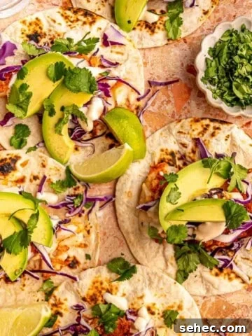 Three fish tacos topped with avocado.