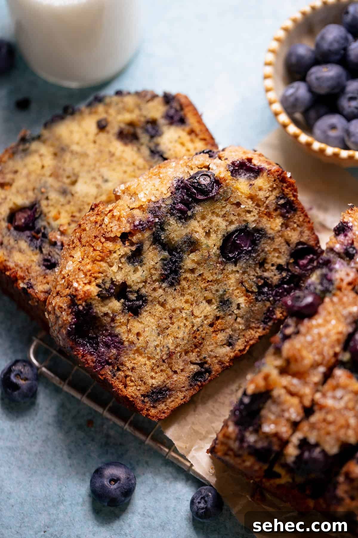 Sugar Crusted Blueberry Banana Bread 2 Sliced blueberry banana bread served with a glass of milk and fresh blueberries.
