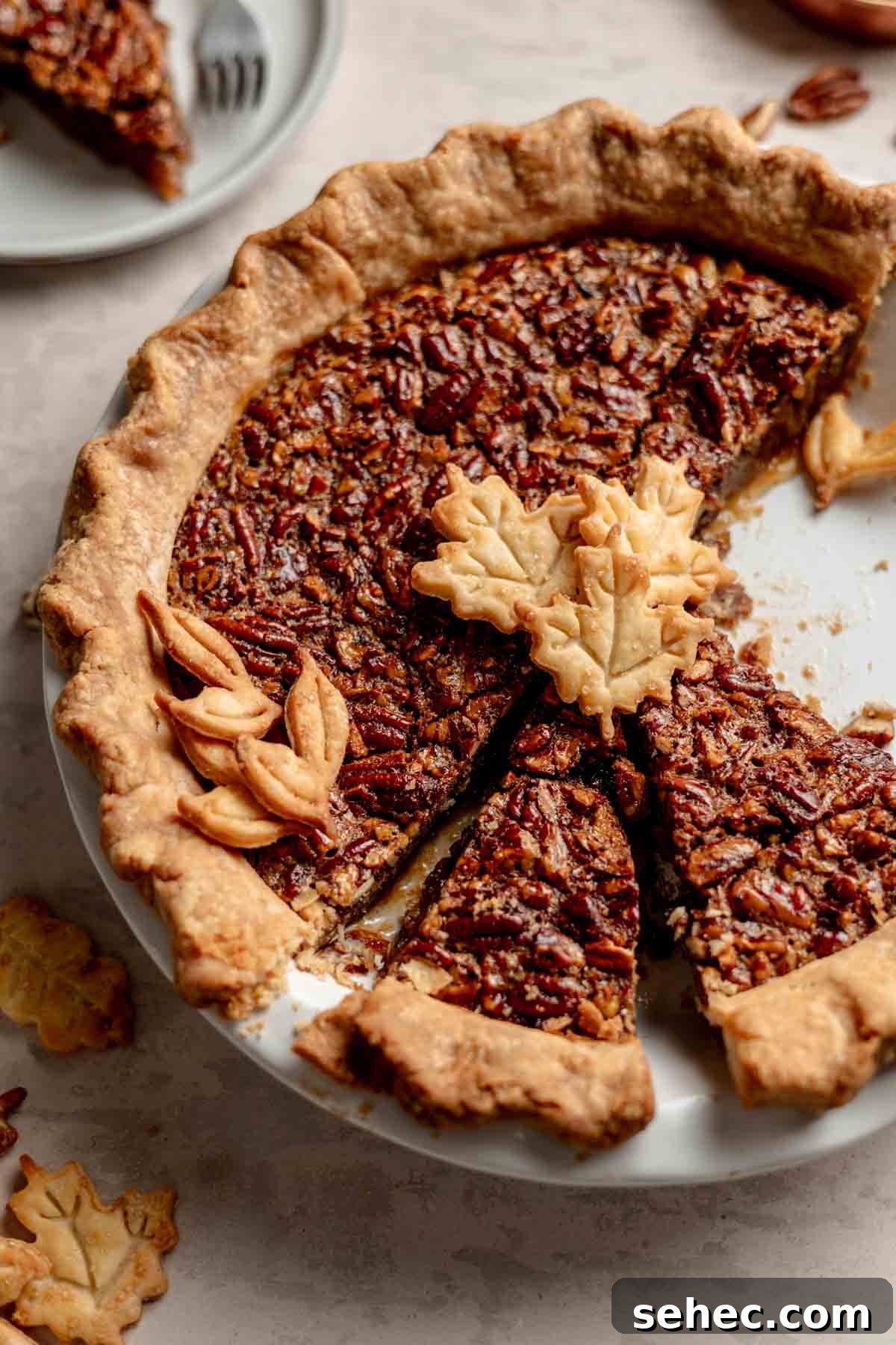 Gluten Free Pecan Pie Recipe with Classic Southern Flavor 2 Gluten-Free Pecan Pie sliced in a white pie pan topped with leaf shaped pie cutouts.