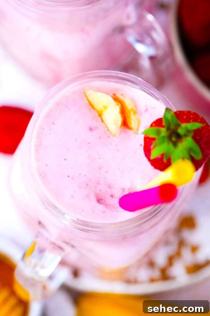 Creamy Strawberry Banana Smoothie Recipe 8 Overhead shot of strawberry banana smoothie garnished with fresh strawberries and banana slices.