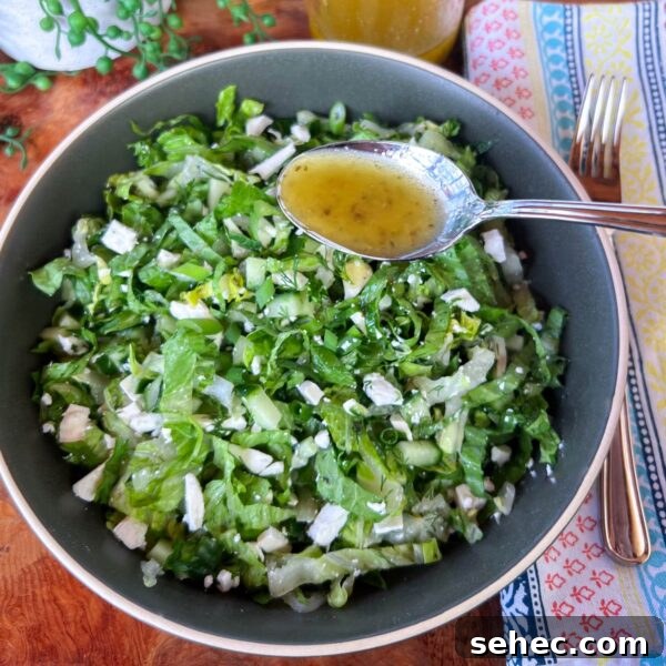 Maroulosalata Greek Green Salad with Fresh Herbs 5 salad in bowl with spoon ful of dressing hovering