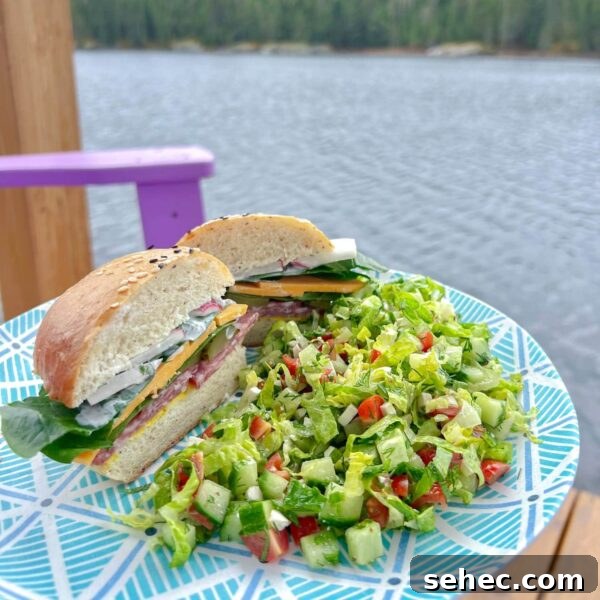 Maroulosalata Greek Green Salad with Fresh Herbs 6 salami bun sandwich on plate with simple green salad by lake