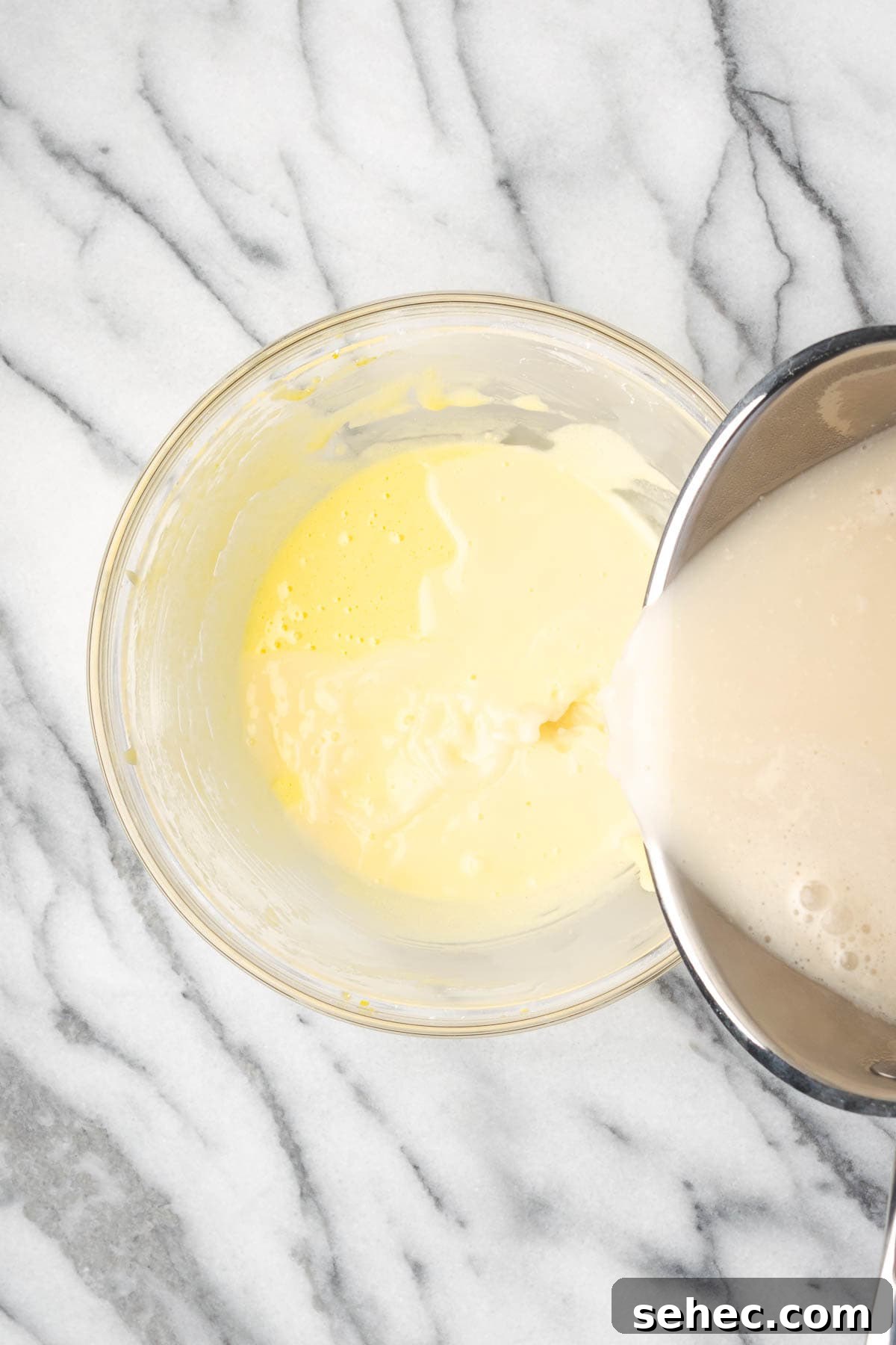 Homemade Banana Pudding Recipe From Scratch 6 Hot milk being slowly added to the egg yolk mixture.