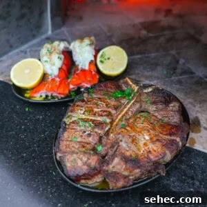 Peter Luger Surf and Turf Steak and Lobster Recipe 11 Close-up of Peter Luger surf and turf with lobster and steak in front of glowing embers.