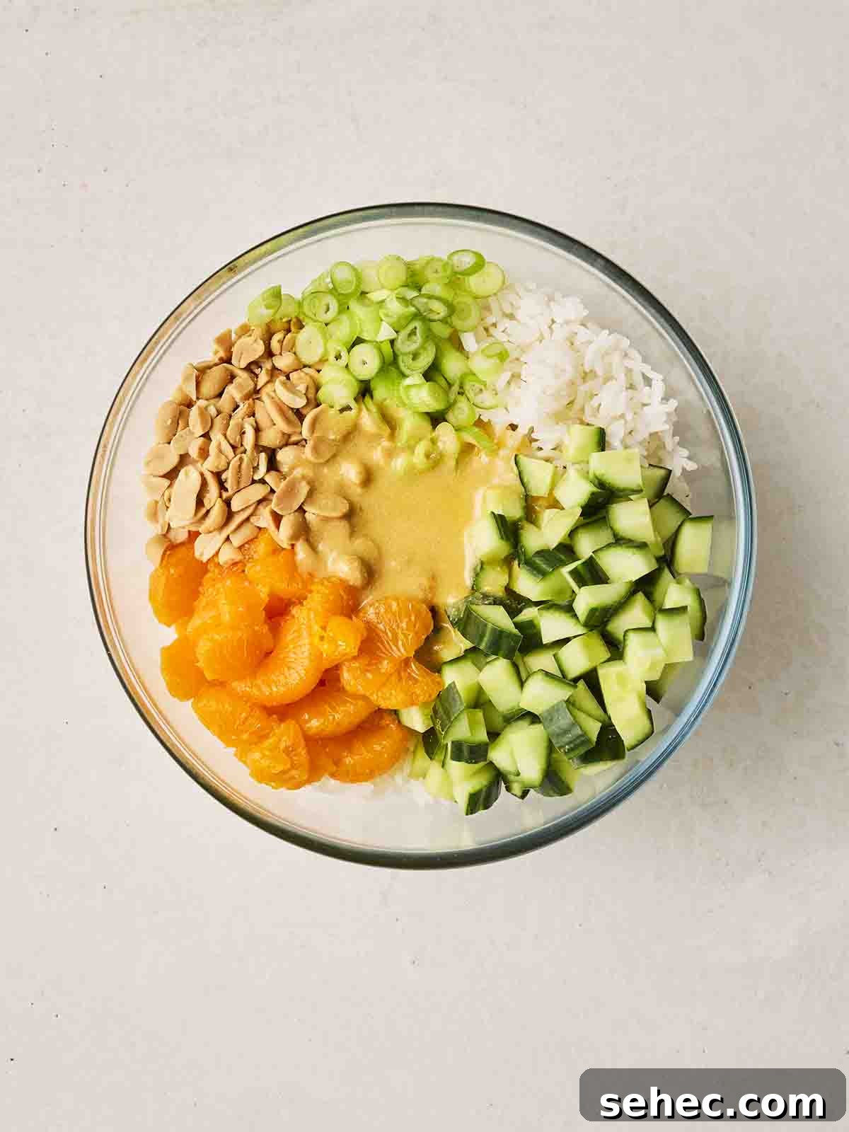 Rice Salad with Fresh Vegetables and Herbs 6 The ingredients for making a rice salad in bowl together, ready to be mixed with the dressing that's on top.