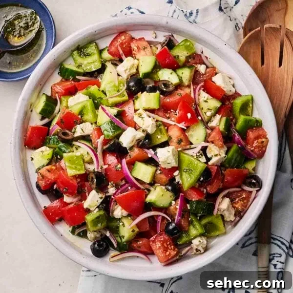 Rice Salad with Fresh Vegetables and Herbs 7 A white bowl with chopped Greek Salad, with utensils around the side.