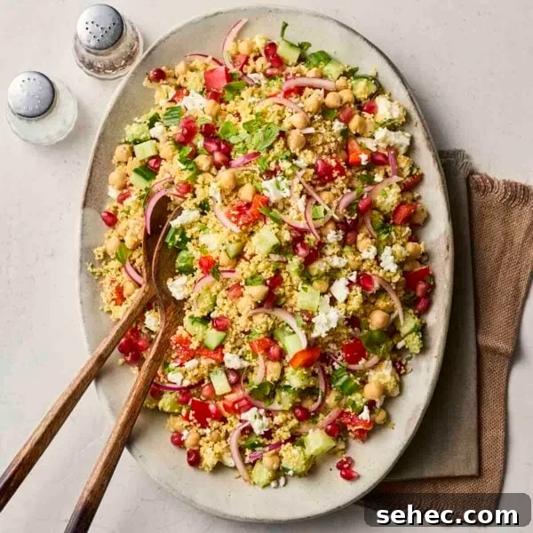 Rice Salad with Fresh Vegetables and Herbs 9 A platter with a colourful couscous salad on, sitting on a white counter with salad servers ready to dish out.