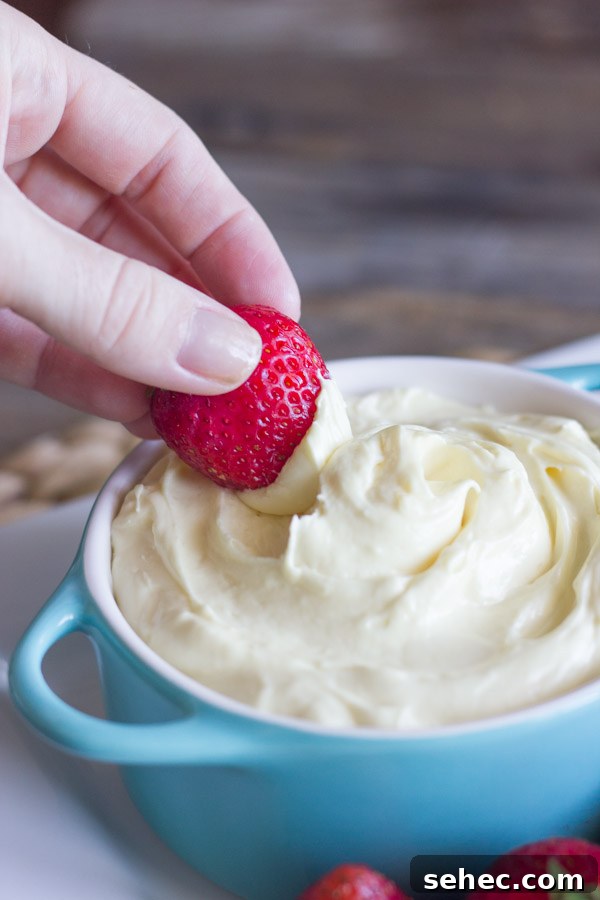 Creamy Vanilla Pudding Fruit Dip Recipe 5 Easy creamy vanilla pudding fruit dip in a bowl with a strawberry being dipped into it.