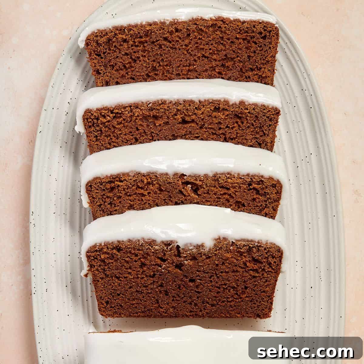 Slices of gingerbread loaf, sitting on a white oval dish.