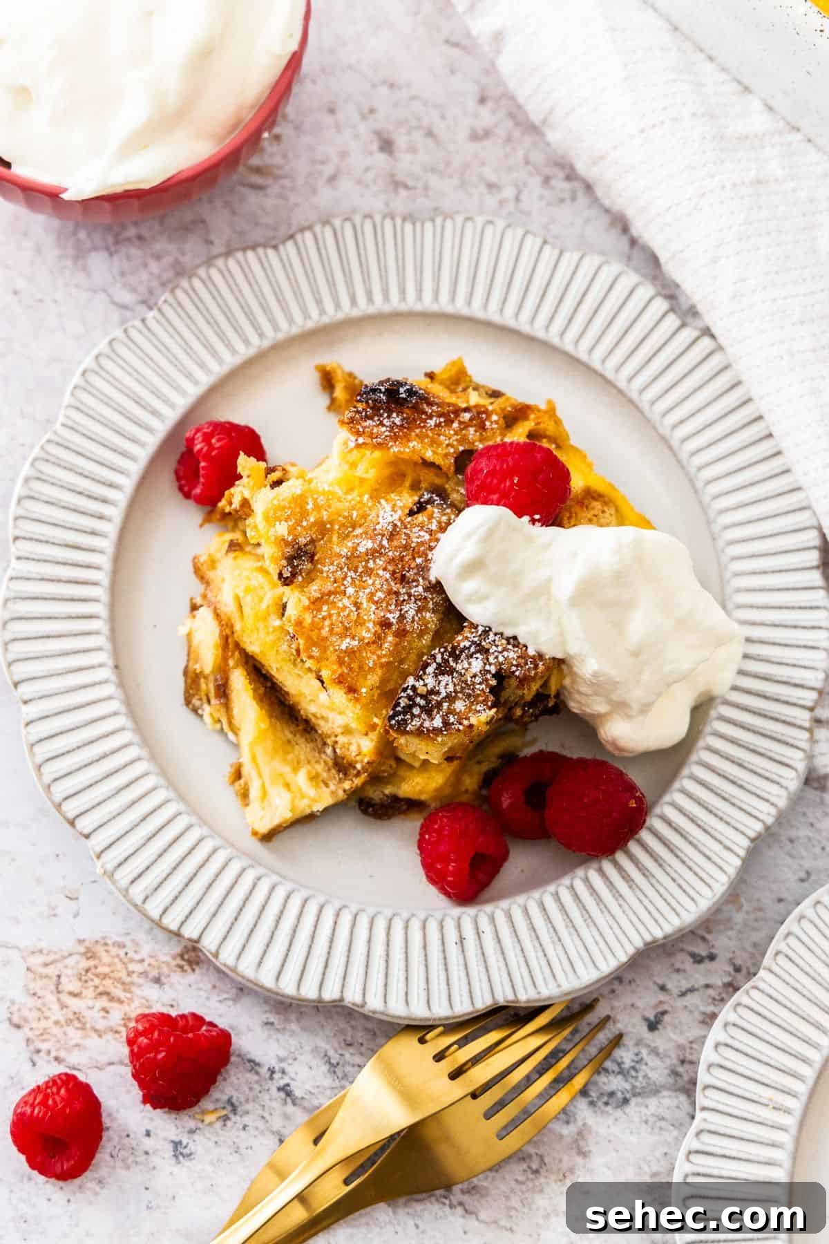 Panettone Bread and Butter Pudding Recipe 7 Plate with serve of Panettone Bread and Butter Pudding, topped with whipped cream and fresh raspberries.