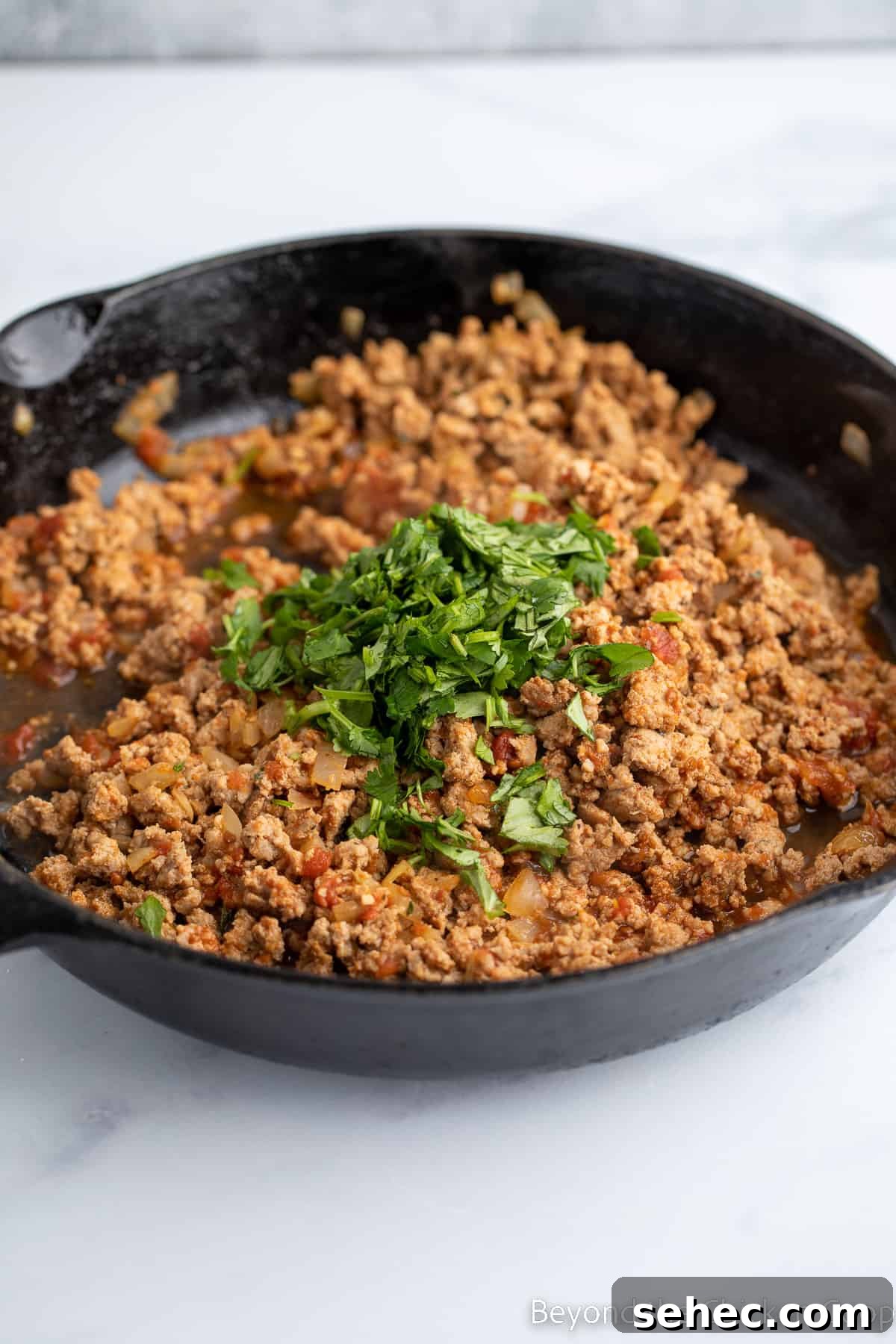 Ground Turkey Enchiladas Recipe 7 Fresh cilantro added to a pan with meat.