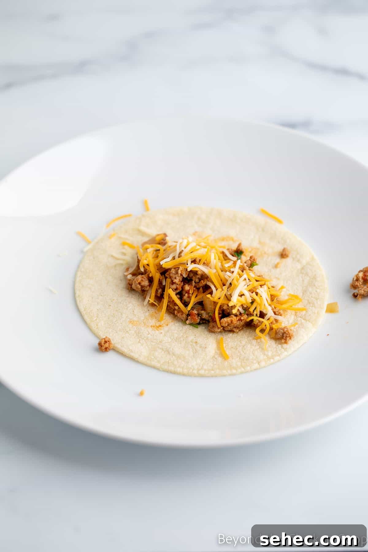 Ground Turkey Enchiladas Recipe 8 Meat filling and cheese on a tortilla.