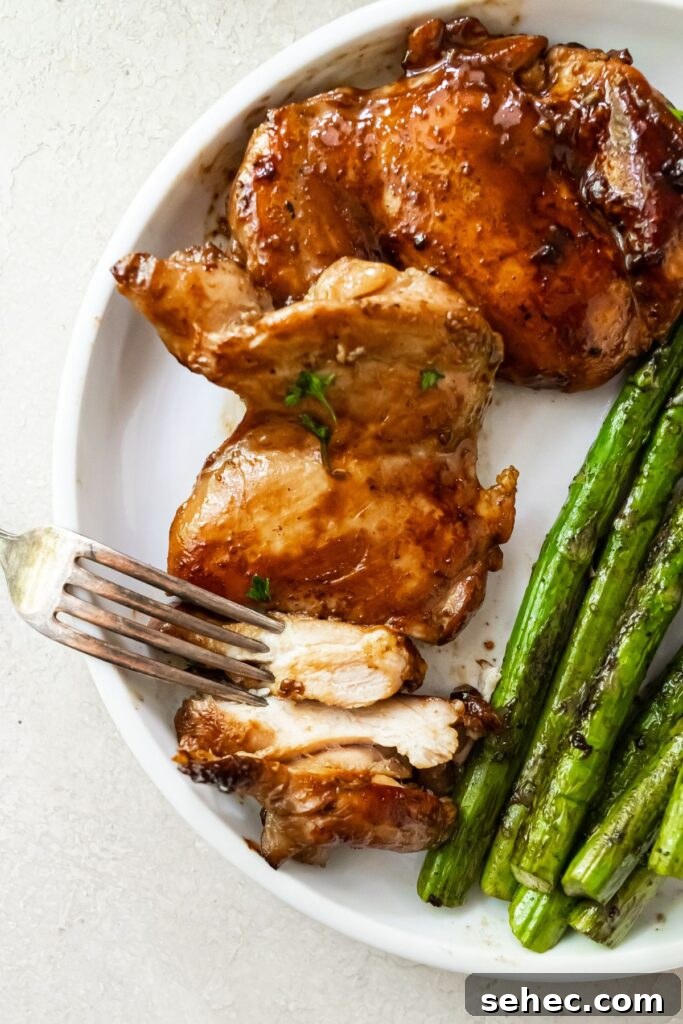 Blackstone Griddle Teriyaki Chicken Thighs 2 sliced teriyaki blackstone chicken thighs on a white plate with griddled asparagus