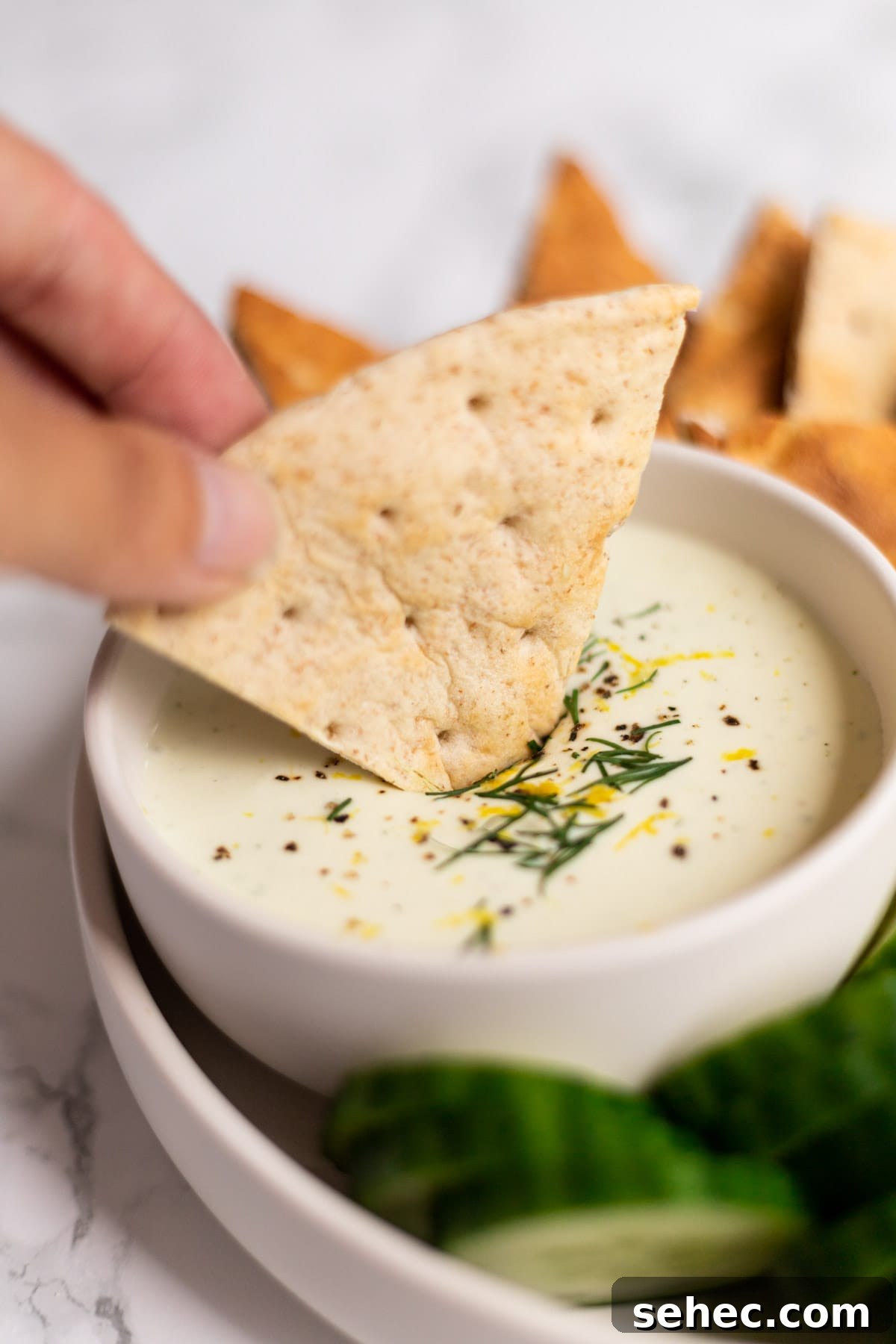 Creamy Whipped Feta Dip with Honey and Herbs 5 A hand dipping pita bread into whipped feta dip.