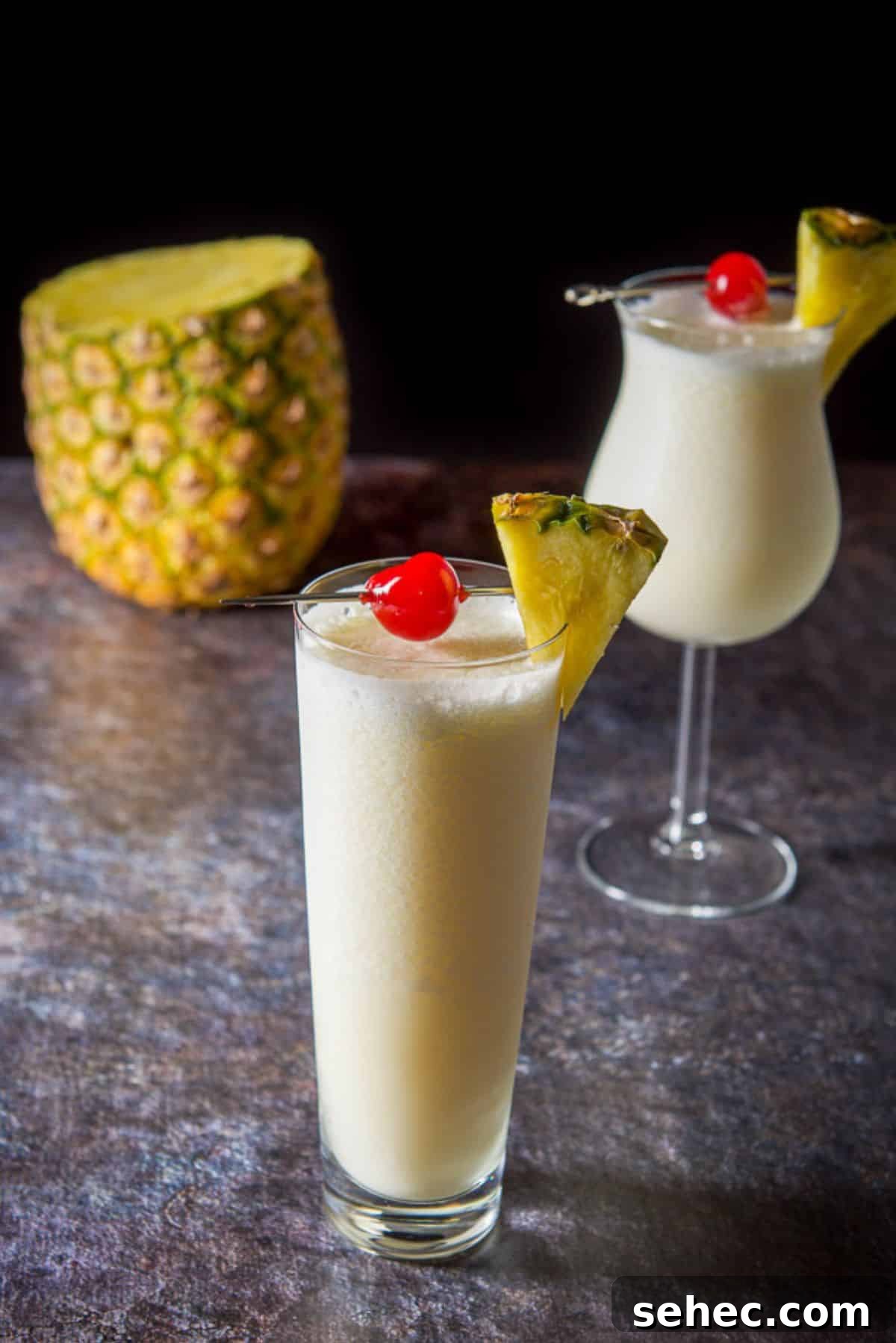 Two glasses with the piña colada with a pineapple in the background