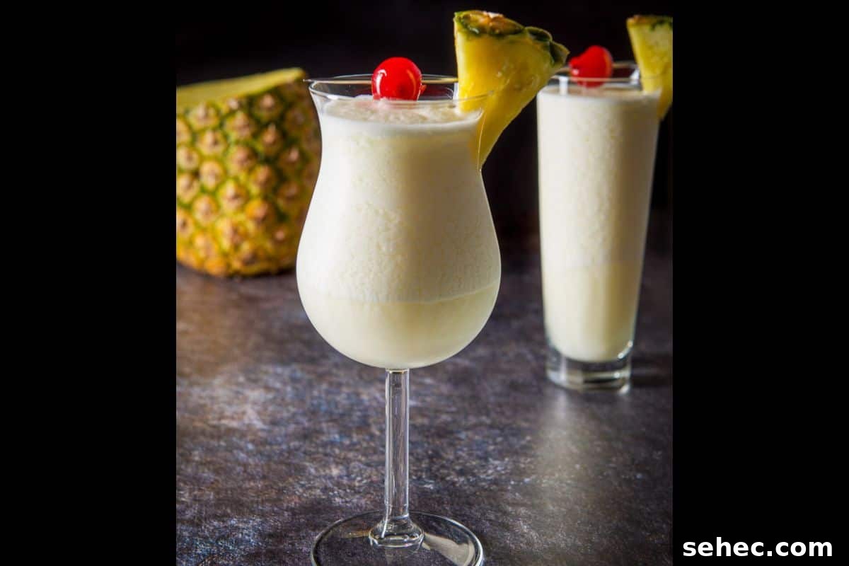 Vertical view of the piña colada cocktail in two glasses with pineapple and cherries on the rim
