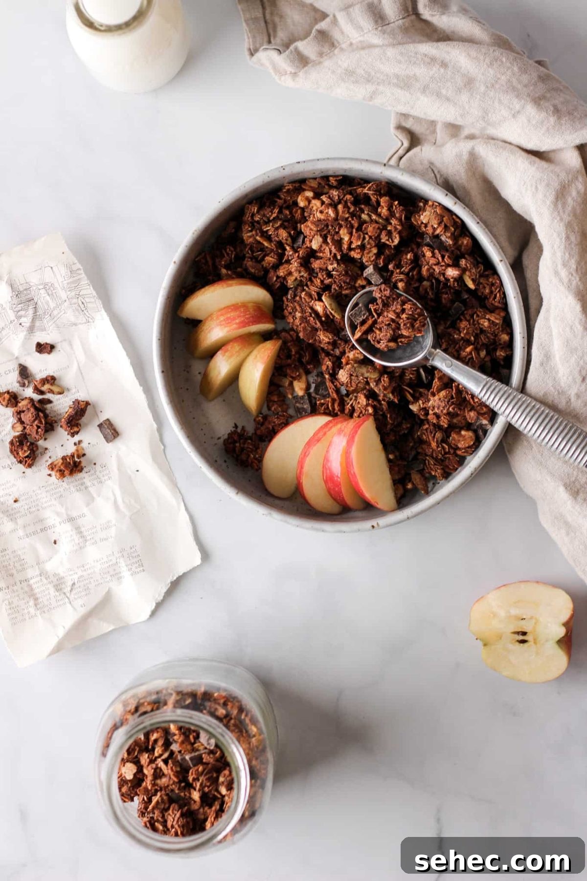 Chocolate Granola Recipe a bowl of chocolate chunk granola with a spoon and sliced apples for food photography