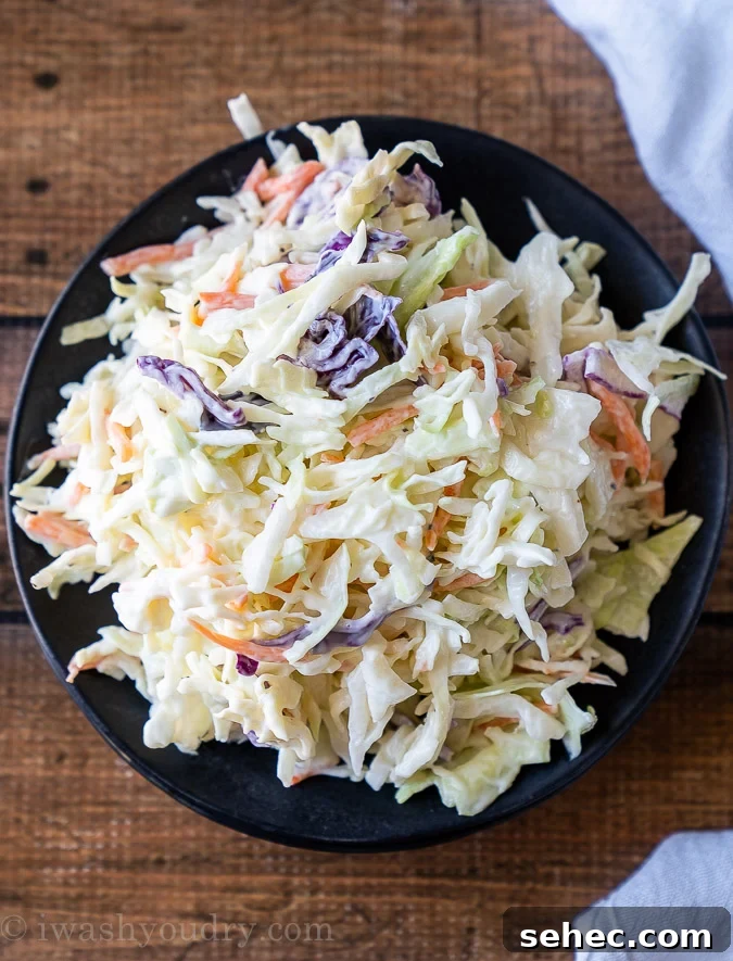 Creamy Coleslaw Recipe with Crunchy Cabbage and Carrots 4 Top down picture of a black plate with coleslaw salad piled high.