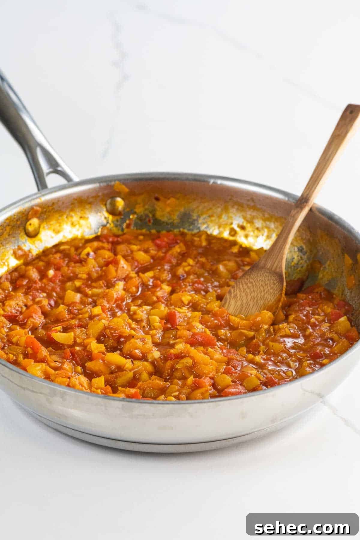 bell pepper sauce in a pan with a wooden spoon