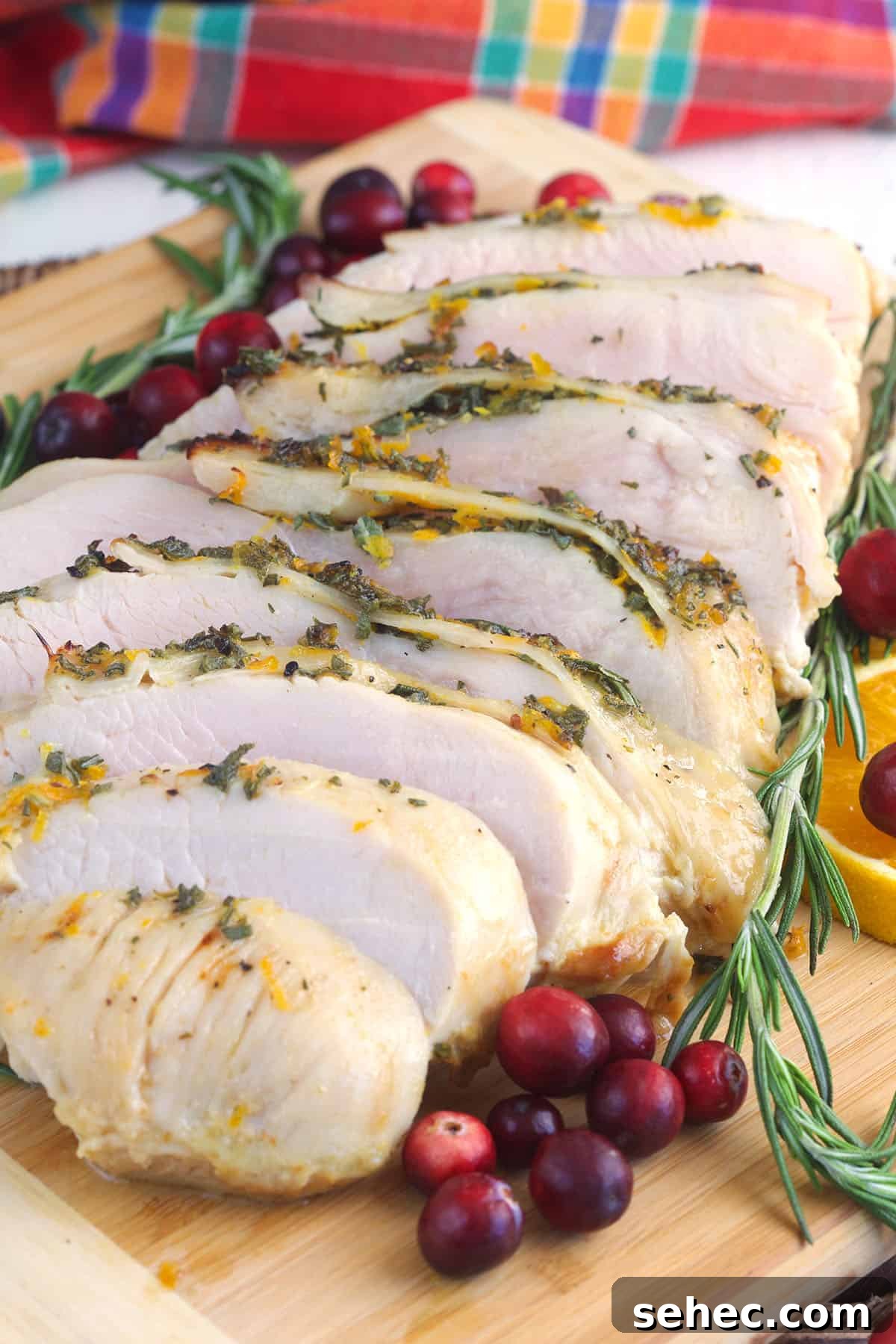 Roasted Turkey Breast with Honey Butter Glaze 5 A sliced turkey breast is presented next to cranberries and herbs.