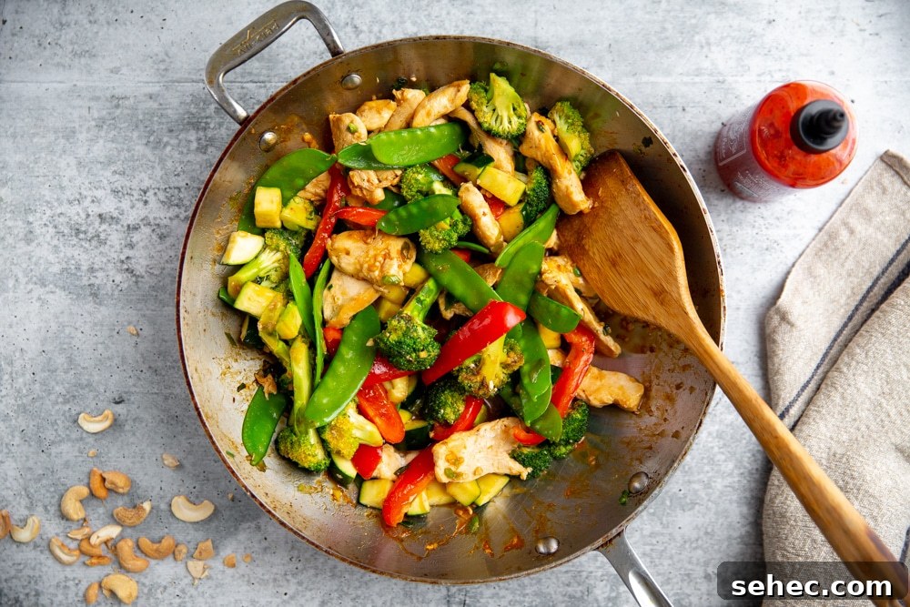 Stir Fry Recipe with Any Vegetables and Meat 11 Healthy stir fry in a wok with sriracha alongside.