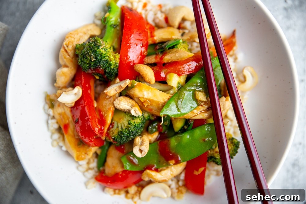 Stir Fry Recipe with Any Vegetables and Meat 3 Close up of a stir fry in a bowl over rice with chopsticks.