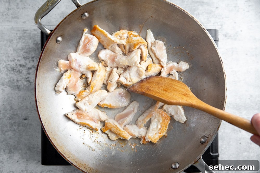 Stir Fry Recipe with Any Vegetables and Meat 5 Process shot showing partially cooked chicken in a wok.
