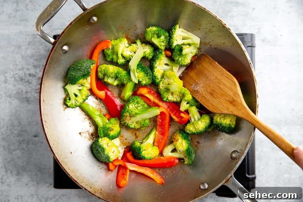 Stir Fry Recipe with Any Vegetables and Meat 6 Process shot showing hardy vegetables cooking in a wok for the healthy stir fry recipe.